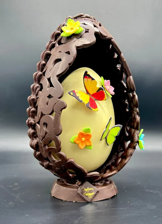 Uovo di cioccolato aperto con un nido, farfalle e fiori